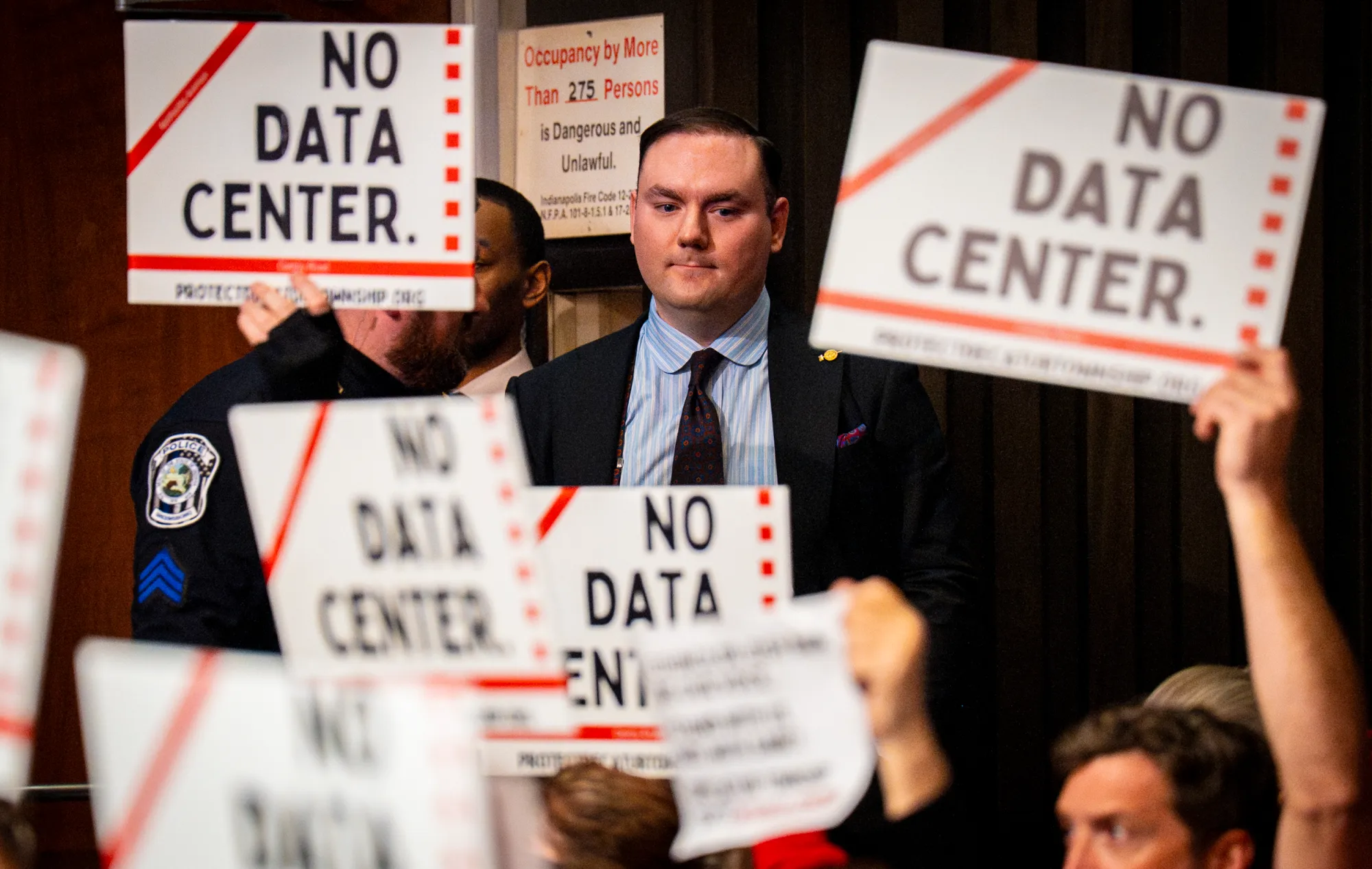 Joshua Bain at a public meeting, surrounded by No Data Center signs.